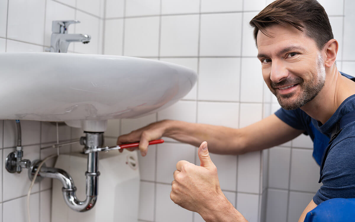 Plumber repairing the trap under a bathroom sink